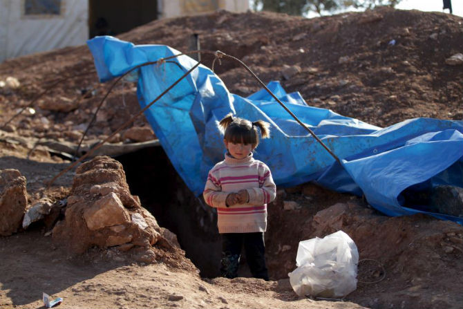 Bé gái Syria đứng trước lối vào “ngôi nhà” tạm bợ ngày 26/12.