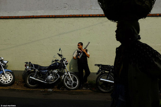 Nhân viên an ninh Guatemala mang theo súng đứng gác ở một khu chợ trong thành phố.