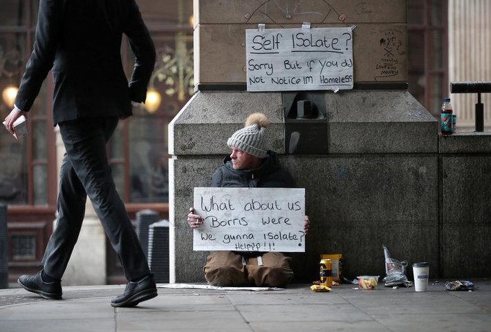 Người đàn ông ngồi bên ngoài tàu điện ngầm Westminster ở London, Anh, và giơ tấm biển cầu xin sự giúp đỡ hôm 19/3.