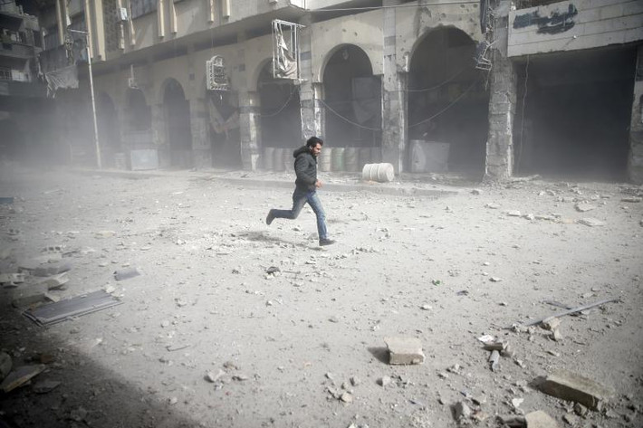 Người đàn ông tháo chạy trong một vụ không kích ở thị trấn Douma, Đông Ghouta, Syria, ngày 6/2.
