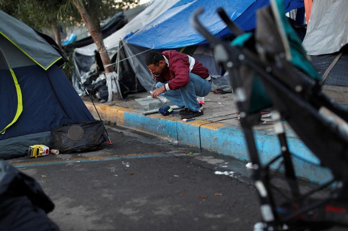 Người đàn ông rửa mặt tại khu lán trại ở Tijuana ngày 9/12. Điều kiện sống trong những khu trú ẩn tạm bợ này rất thiếu thốn.