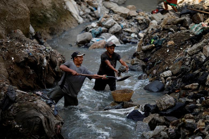 Hai người đàn ông tìm kiếm những mảnh kim loại phế thải tại bãi rác thải ở thành phố Guatemala.