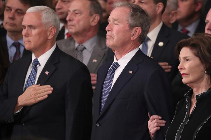 Phó Tổng thống Mỹ Mike Pence (trái) đứng cạnh cựu Tổng thống Bush “con” và phu nhân Laura nhìn linh cữu cố Tổng thống Bush “cha” được đưa vào Mái vòm Rotunda ngày 3/12.