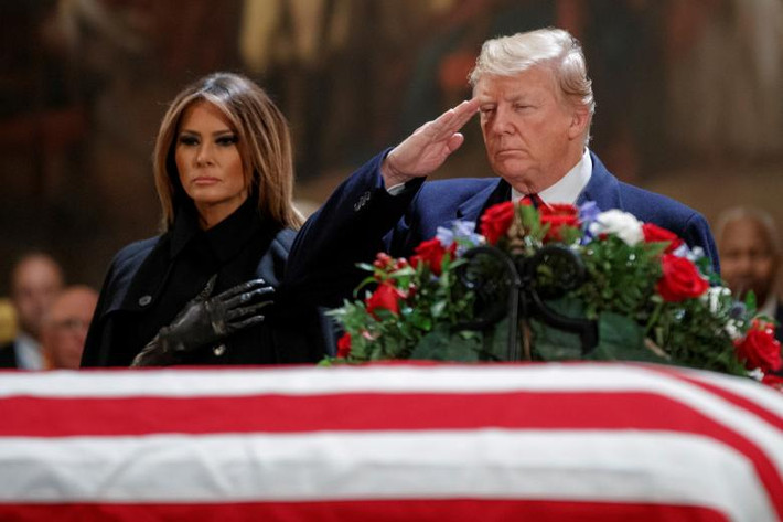 Tổng thống Trump, đứng cạnh Đệ nhất phu nhân Mỹ Melania, chào trước linh cữu cố Tổng thống Bush cha trong Điện Capitol ngày 3/12. (Nguồn ảnh: Reuters)