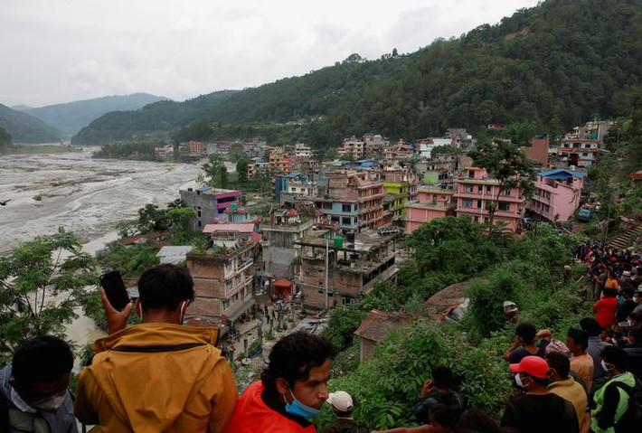 Người dân đứng ở trên cao nhìn nước sông Melamchi tràn bờ vào ngôi làng ở Sindhupalchok ngày 16/6.