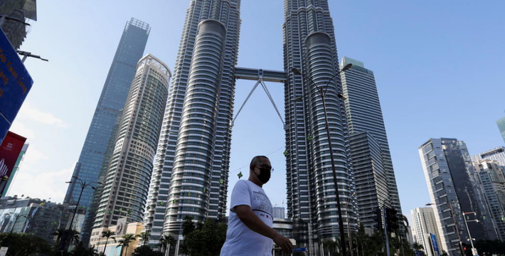 Người đàn ông đeo khẩu trang đi qua một con phố phía trước Tháp đôi Petronas ở thủ đô Malaysia. Ảnh: Reuters.