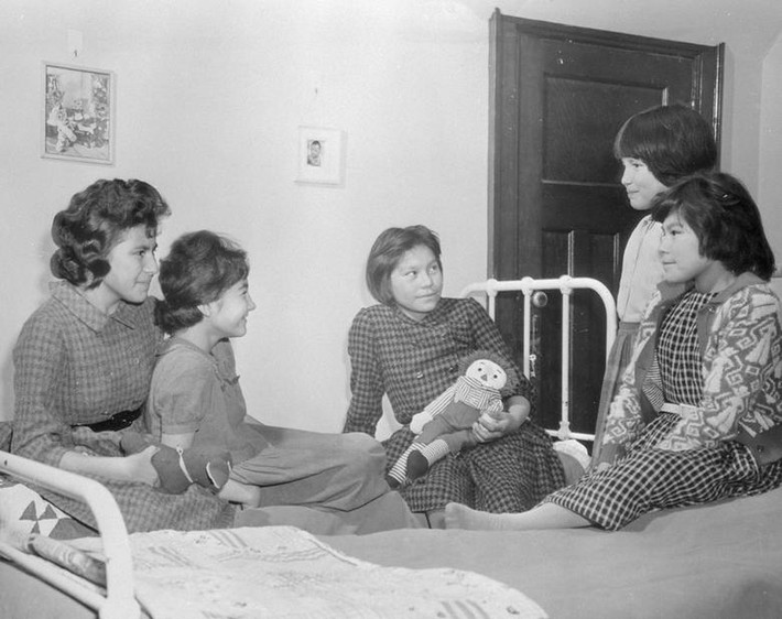 Các học sinh nữ ngồi trên giường trò chuyện trong ký túc xá của trường nội trú Shingwauk Indian ở Sault Ste Marie, Ontario, năm 1960.