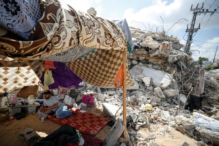 Người đàn ông Palestine nằm nghỉ trong túp lều tạm bợ ở Gaza.