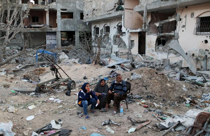 Những người dân Palestine ngồi gần ngôi nhà bị phá hủy ở phía bắc Dải Gaza hôm 1/6.