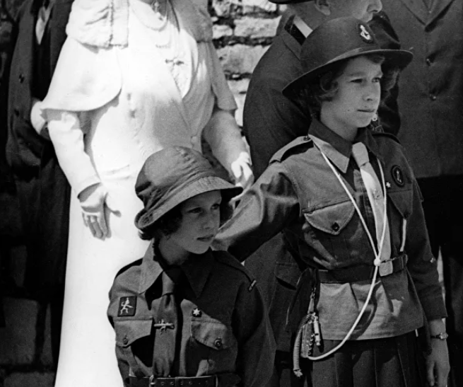 Nữ hoàng Anh Elizabeth II (phải) lúc nhỏ đứng cạnh em gái, Công chúa Margaret, khi theo dõi một sự kiện tại Lâu đài Windsor hồi năm 1938.