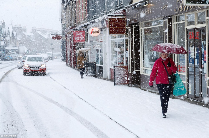 Người đi đường phải che ô khi đi dưới trời mưa tuyết ở Pitlochry. Ảnh: Reuters.