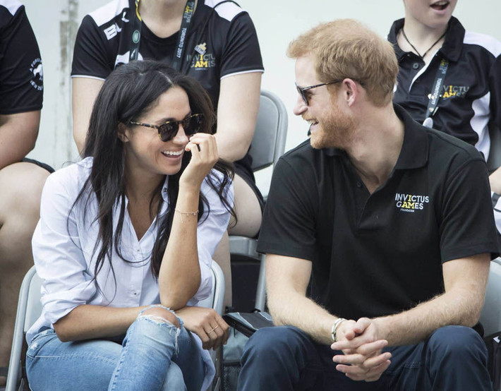 Hoàng tử Harry và nữ diễn viên Meghan vui vẻ trò chuyện khi xem một trận đấu tennis tại giải Invictus Games 2017. Ảnh: Express.