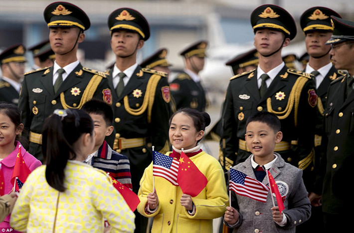 Các em học sinh cầm cờ Mỹ và Trung Quốc đứng chào đón vợ chồng Tổng thống Mỹ Donald Trump tại sân bay. Ảnh: AP.