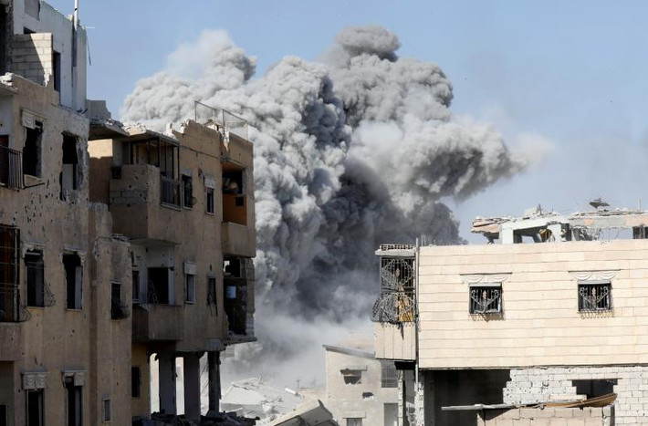 Khói bụi bốc lên sau khi căn cứ của phiến quân IS gần sân vận động ở Raqqa, Syria, bị không kích ngày 4/10. Ảnh: Reuters.