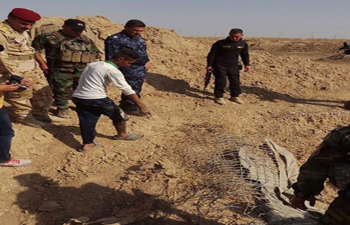 Nhiều người dân địa phương và binh sĩ Iraq đứng tập trung gần một hố chôn tập thể ở Kirkuk. Ảnh: FNA.