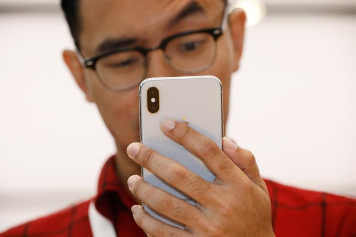 Khách hàng thử tính năng trên chiếc iPhone X tại cửa hàng ở Singapore. Ảnh: Reuters.