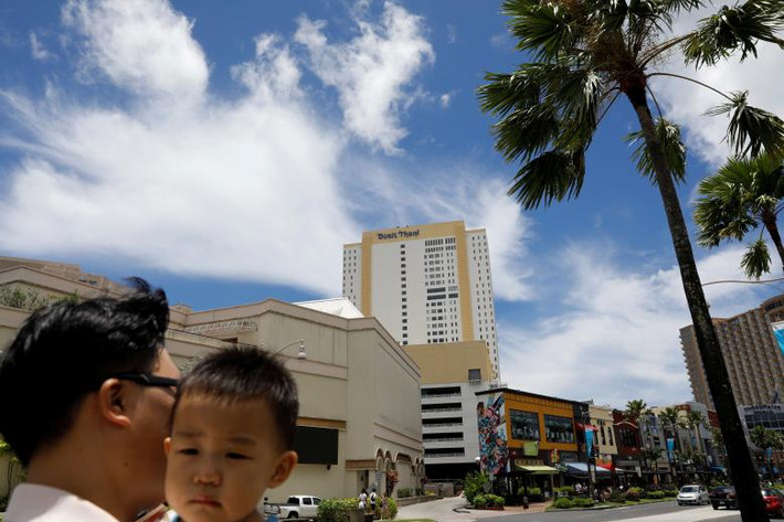 Một du khách Hàn Quốc bế con trên đường phố ở đảo Guam. Ảnh: Reuters.