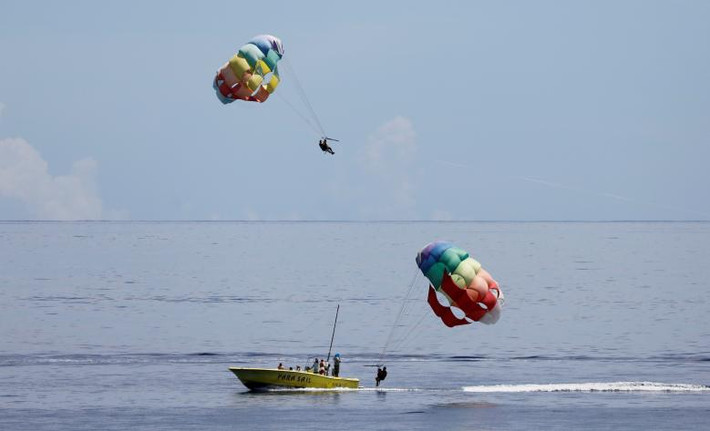 Các du khách chơi nhảy dù ở bãi biển Tumon. Ảnh: Reuters.