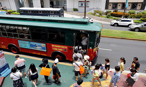 Các du khách lên xe buýt ở Tumon. “Tôi sẽ không rút ngắn kỳ nghỉ của mình vì lời đe dọa mới nhất của Triều Tiên”, Zhao Liang, 35 tuổi, đến từ Bắc Kinh (Trung Quốc), cho biết. Ảnh: Reuters.