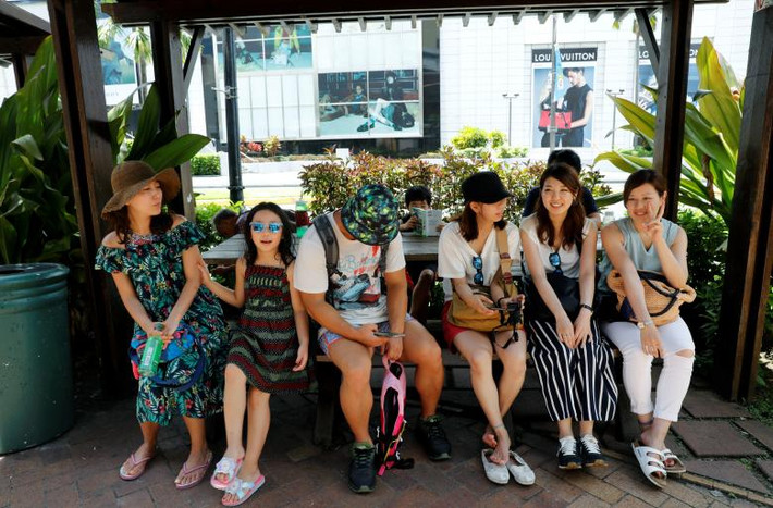 Một số du khách ngồi nghỉ ở quận du lịch Tumon trên đảo Guam. Ảnh: Reuters.