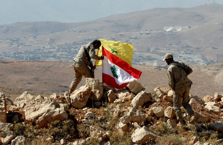 Chiến binh Hezbollah cắm cờ Lebanon và cờ của phong trào này ở Juroud Arsal. Ảnh: Reuters.