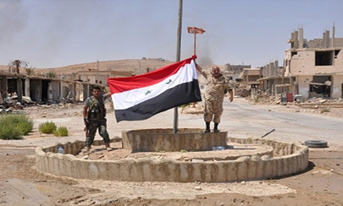 Hai binh sĩ cầm lá cờ Syria tại một địa điểm ở thị trấn al-Sukhnah sau giải phóng. Ảnh: FNA.