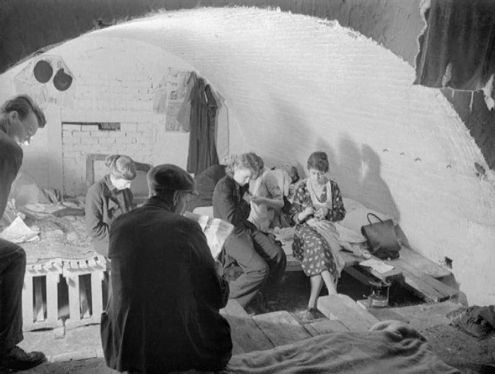 Một số người đọc báo trong nơi tránh bom ở London năm 1940. Nhà của họ đã bị bom đạn của phát xít Đức phá hủy. Ảnh: ATI.