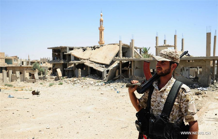 Binh sĩ Syria đứng trước tòa nhà bị phá hủy trong các cuộc giao tranh tại al-Sukhnah trước đó. Ảnh: THX.