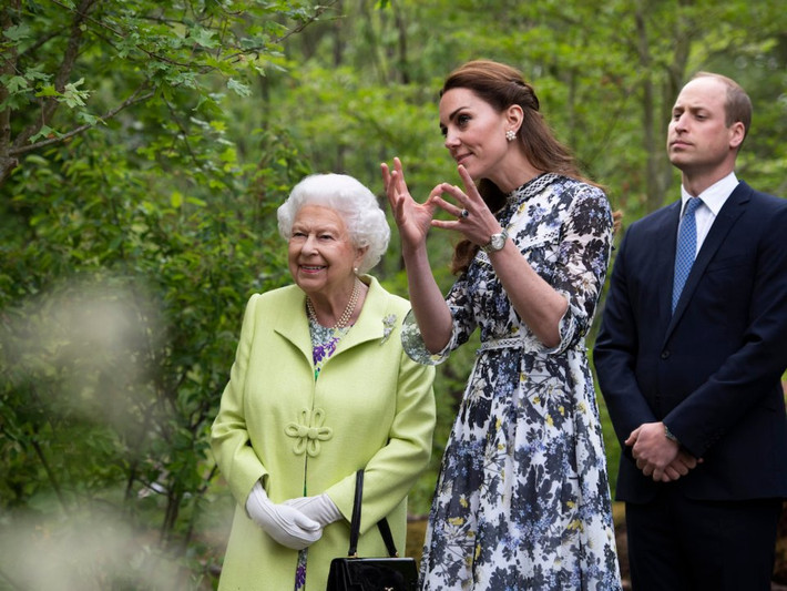 Công nương Kate đang giới thiệu với Nữ hoàng Elizabeth II về khu vườn mà cô thiết kế dành cho Triển lãm hoa Chelsea ở London, trong khi Hoàng tử William đứng cạnh trông giống như một vệ sĩ bảo vệ cho vợ mình.