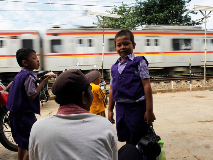 Học sinh Indonesia chờ đoàn tàu qua trên đường trở về nhà sau khi dự lễ khai giảng ở trường mẫu giáo tại thủ đô Jakarta. Ảnh: Reuters.