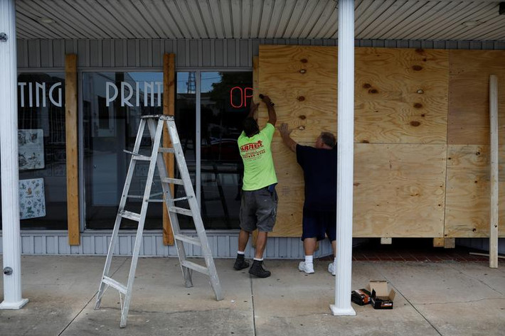 Hai người đàn ông gia cố tòa nhà ở Cocoa, Florida, trước khi bão ập tới. Ảnh: Reuters.