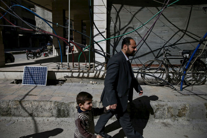 Cư dân đi bộ qua đường dẫn ống nước chằng chịt ở vùng Douma, Damascus, Syria, ngày 7/3/2016.
