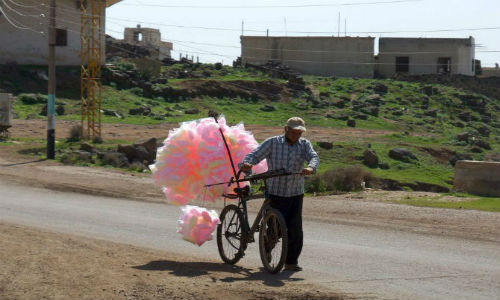 Người đàn ông Syria rong ruổi trên con đường ở thị trấn al-Ghariyah al-Gharbiyah, tỉnh Daraa để bán kẹo bông ngày 29/2.