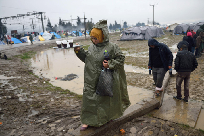 Khoảng 14.000 ngươi tị nạn trên thế giới đang ở Idomeni, nơi họ đang phải sống trong điều kiện tồi tàn vì những trận mưa kéo dài. Ảnh: Người phụ nữ tị nạn đi bộ tại khu trại tạm bợ gần làng Idomeni.