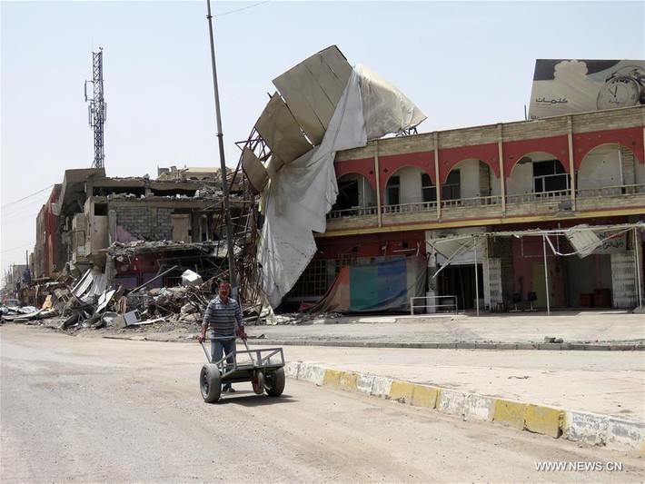Người đàn ông đẩy xe đi qua những tòa nhà đổ nát trong khu vực mới giải phóng ở Tây Mosul. Ảnh: THX.