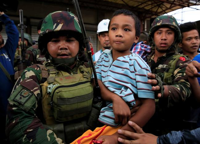 Một binh sĩ Philippines bế bé trai vừa được giải cứu cùng 20 người dân khác tại thành phố Marawi hôm 31/5.