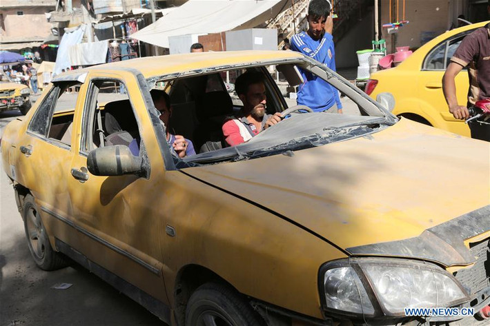Hai người đàn ông ngồi trong chiếc ô tô không có kính chắn gió trên đường phố Tây Mosul ngày 27/5. Ảnh: THX.