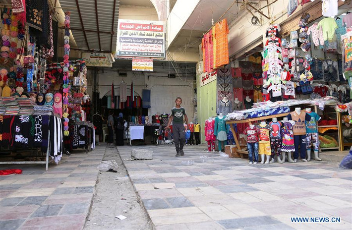 Một bé trai đi qua những cửa hàng quần áo tại khu vực mới giải phóng ở Tây Mosul hôm 27/5. Ảnh: THX.