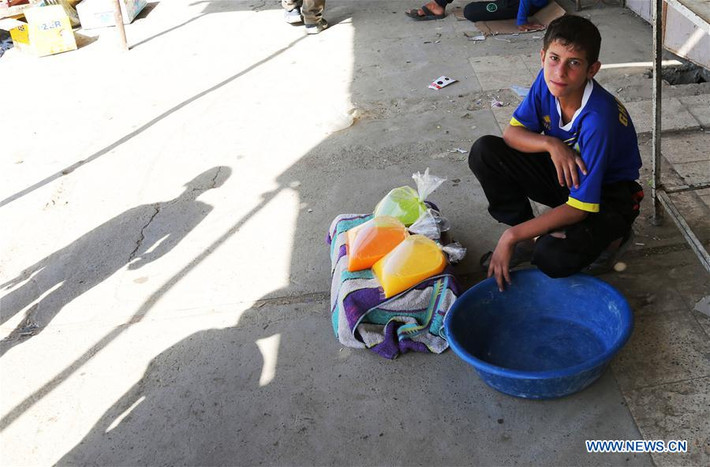 Bé trai Iraq ngồi bán những túi nước ép ở Tây Mosul. Ảnh: THX.