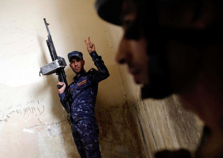 Một cảnh sát Iraq giơ tay biểu tượng chiến thắng trong cuộc giao tranh với IS ở Mosul.