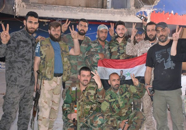 Các binh sĩ Syria giơ tay biểu tượng chiến thắng trong một bức ảnh chụp chung trên chiến trường Đông Damascus. Ảnh: FNA.