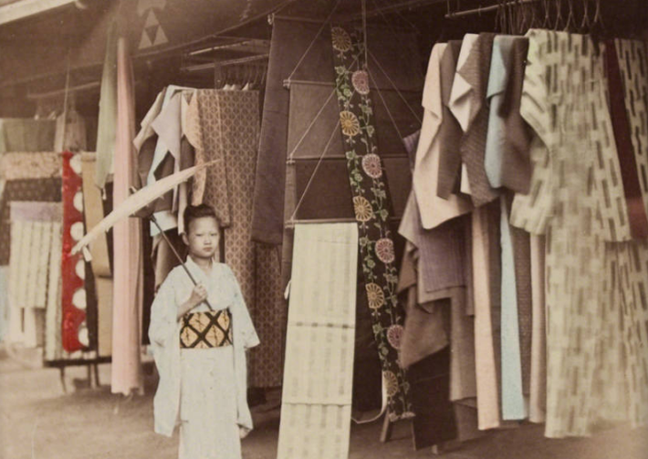 Một em nhỏ đứng trước cửa hàng quần áo vào khoảng những năm 1890. Ảnh: ATI.