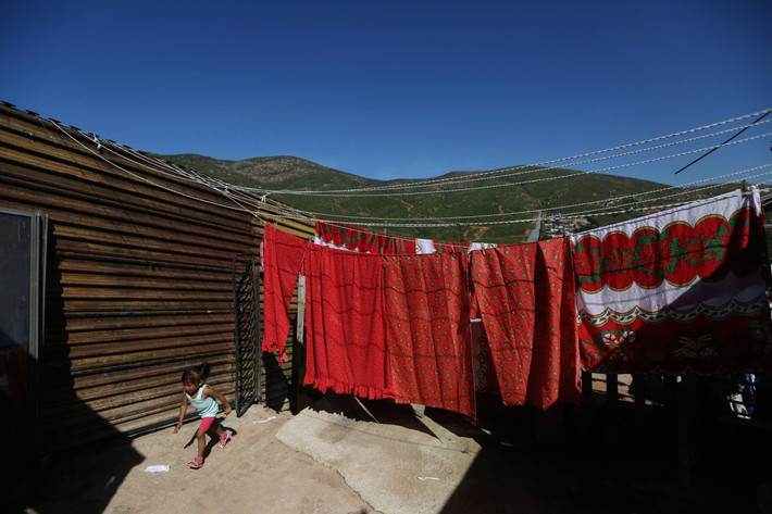 Một bé gái chạy bên ngoài nhà gần hàng rào ở vùng ngoại ô thành phố Tijuana, Mexico. Ảnh: BI.