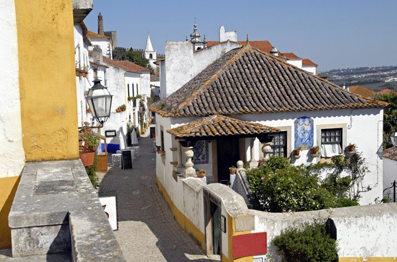 Làng Obidos thuộc tỉnh Estremadura (Bồ Đào Nha) là một trong những điểm đến thu hút du khách năm châu. Ngôi làng bí ẩn ở Châu Âu này đẹp mỹ miều nằm trên đỉnh đồi và được bao quanh bằng tường thành kiên cố. Những bức tường, con đường, quảng trường và thành trì đồ sộ là điểm nhấn của ngôi làng đẹp như tranh vẽ này. Đến đây, bạn sẽ có cơ hội ngắm nhìn vẻ đẹp trường tồn của lâu đài thời trung cổ Obidos, Nhà thờ Xứ đạo Santa Maria, quán cà phê san sát và những ngôi nhà màu trắng được tô điểm bằng chậu hoa rực rỡ.