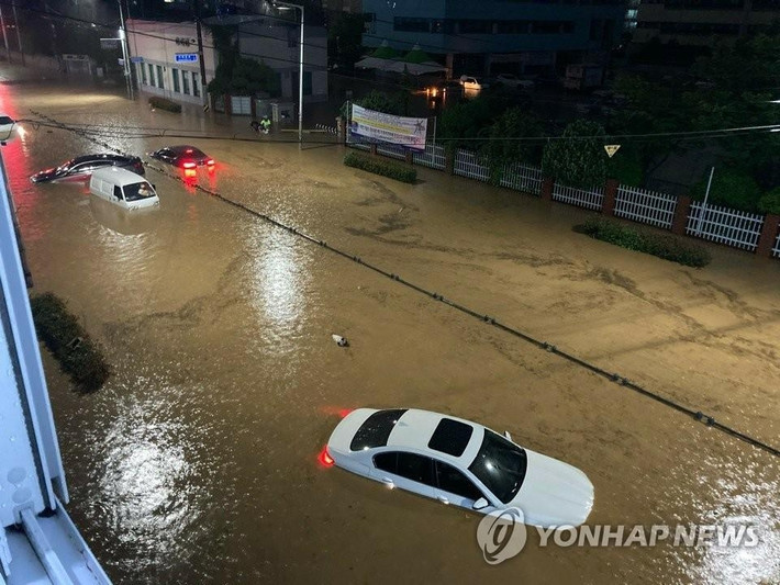 Những chiếc ô tô di chuyển trên con đường ngập nước ở Busan ngày 23/7.