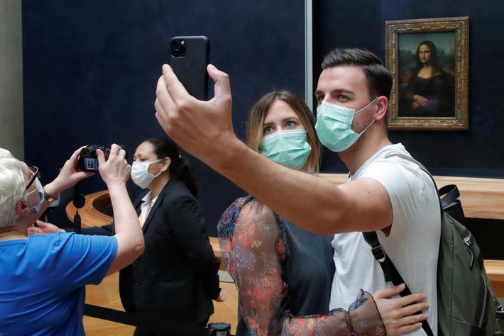 Du khách đeo khẩu trang chụp ảnh "tự sướng" trước bức họa "Mona Lisa" tại Bảo tàng Louvre ở Paris, Pháp, ngày 6/7.