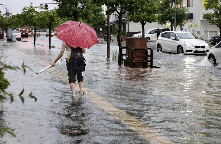Người dân đi bộ qua con phố ngập nước gần nhà ga tàu ở Saga ngày 6/7.