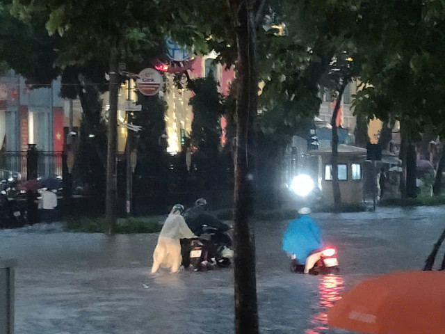 Nhiều người lao động trên tuyến phố Trần Hưng Đạo vẫn vật vã trong đường nước khi màn đêm buông xuống. 075363311ddd9783cecc.jpg