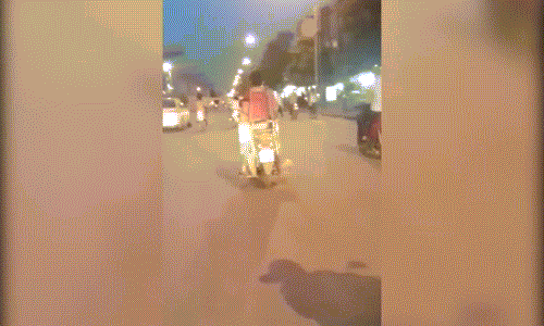 Cậu bé "làm xiếc" sau xe máy của bố trên đường Hà Nội.