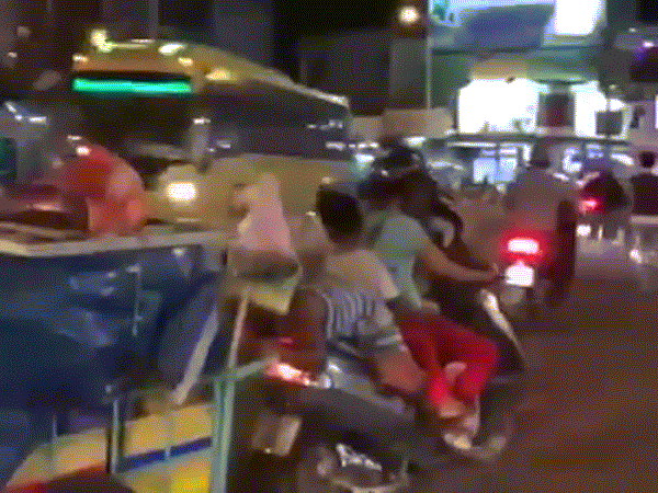 Người mẹ thản nhiên để cậu con trai ngồi quay mặt về phía sau kéo theo xe hàng một cách nguy hiểm nhưng vẫn chạy bon bon trên đường phố.
